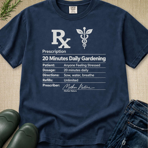 A navy blue graphic t-shirt laid flat on a textured beige surface, styled with green boots, a plant sprig, and blue jeans. The shirt features a white printed prescription-style graphic for '20 Minutes Daily Gardening' with a medical symbol and a signature reading 'Mother Nature'.